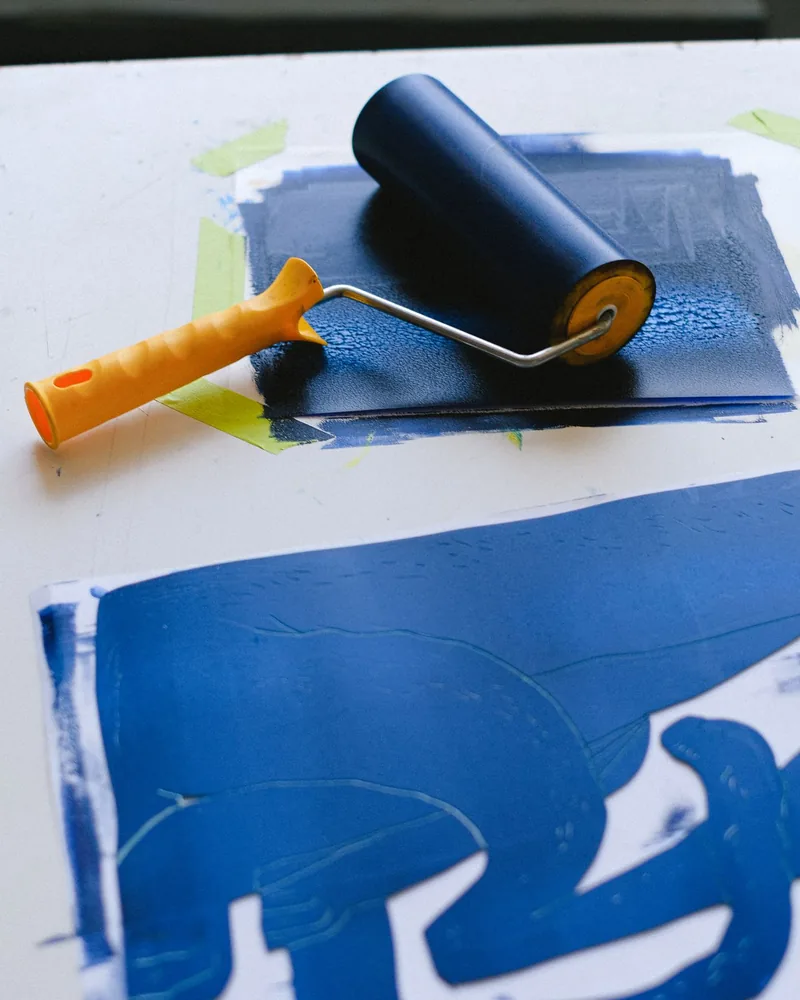Rodillo entintado sobre una plancha y una hoja impresa en un solo color azul