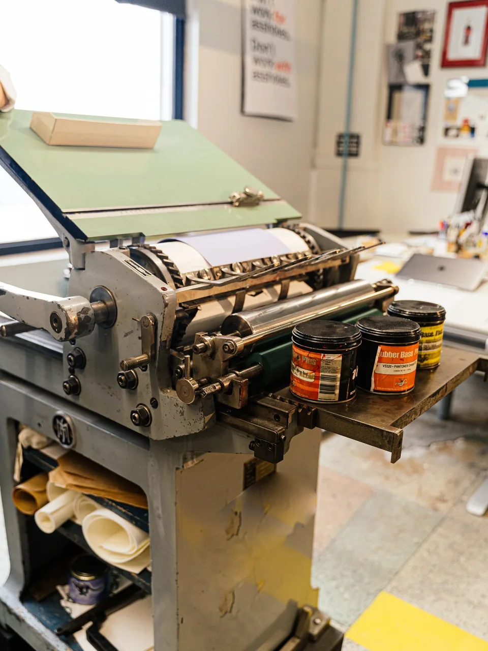 Máquina de impresión de taller con una hoja en el cilindro y botes de tinta junto al cuerpo impresor